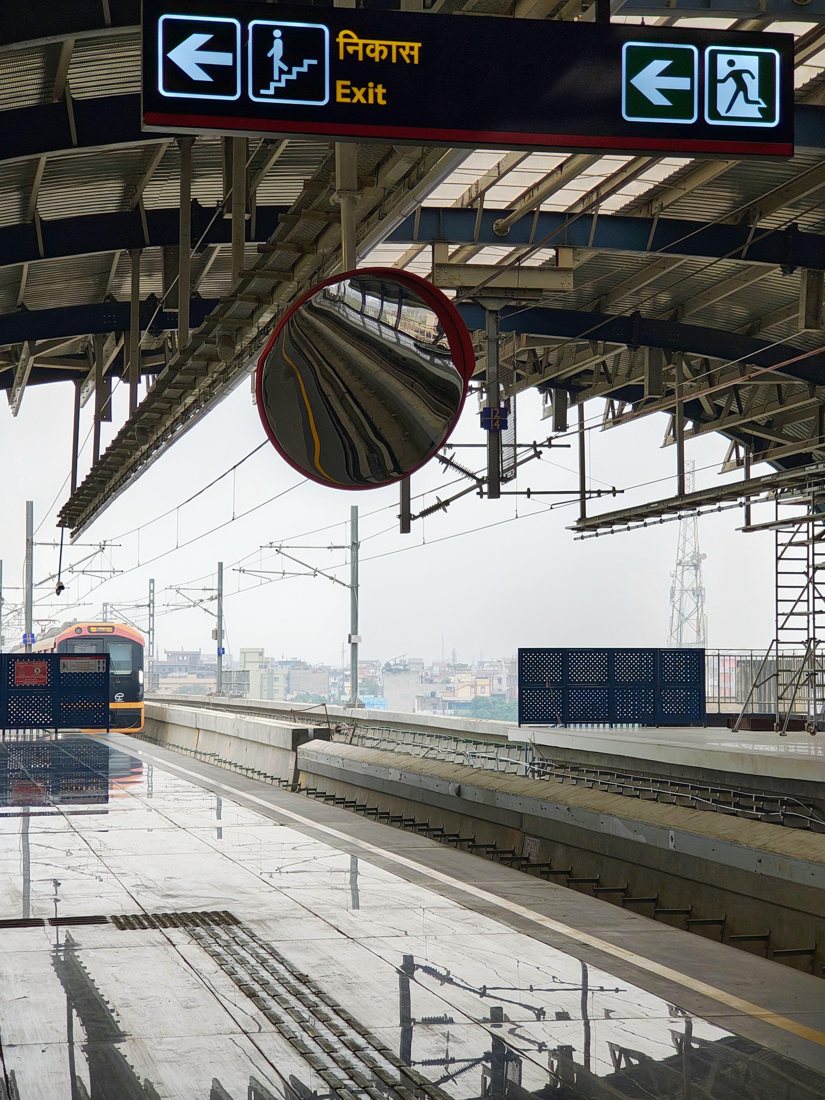 Empty train station platform with directional signs and a distant train.