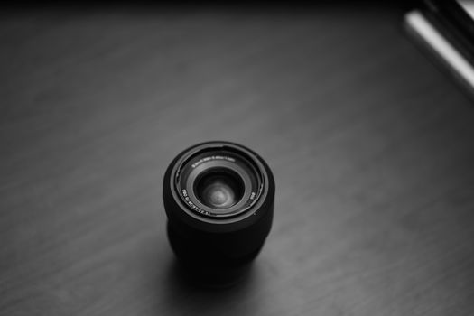 A top-down view of a camera lens in a minimalist black and white setting, showcasing photography essentials.