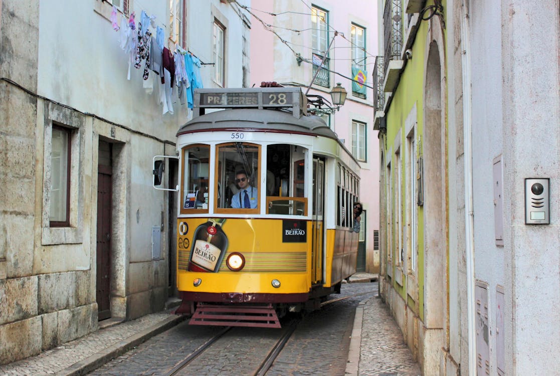 A yellow tram on a tight city street