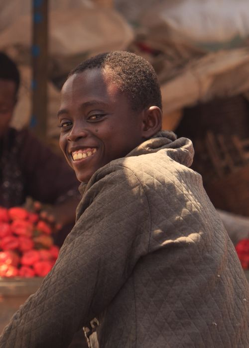 Free A cheerful market vendor smiles with fresh produce in the background. Stock Photo