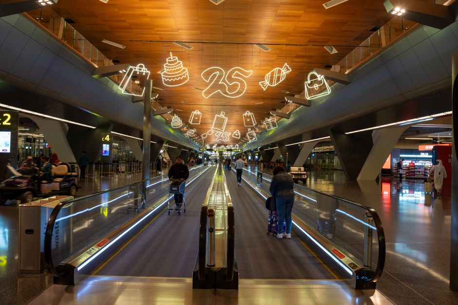 Dynamic scene of travelers at Doha Hamad International Airport with festive ceiling decor.