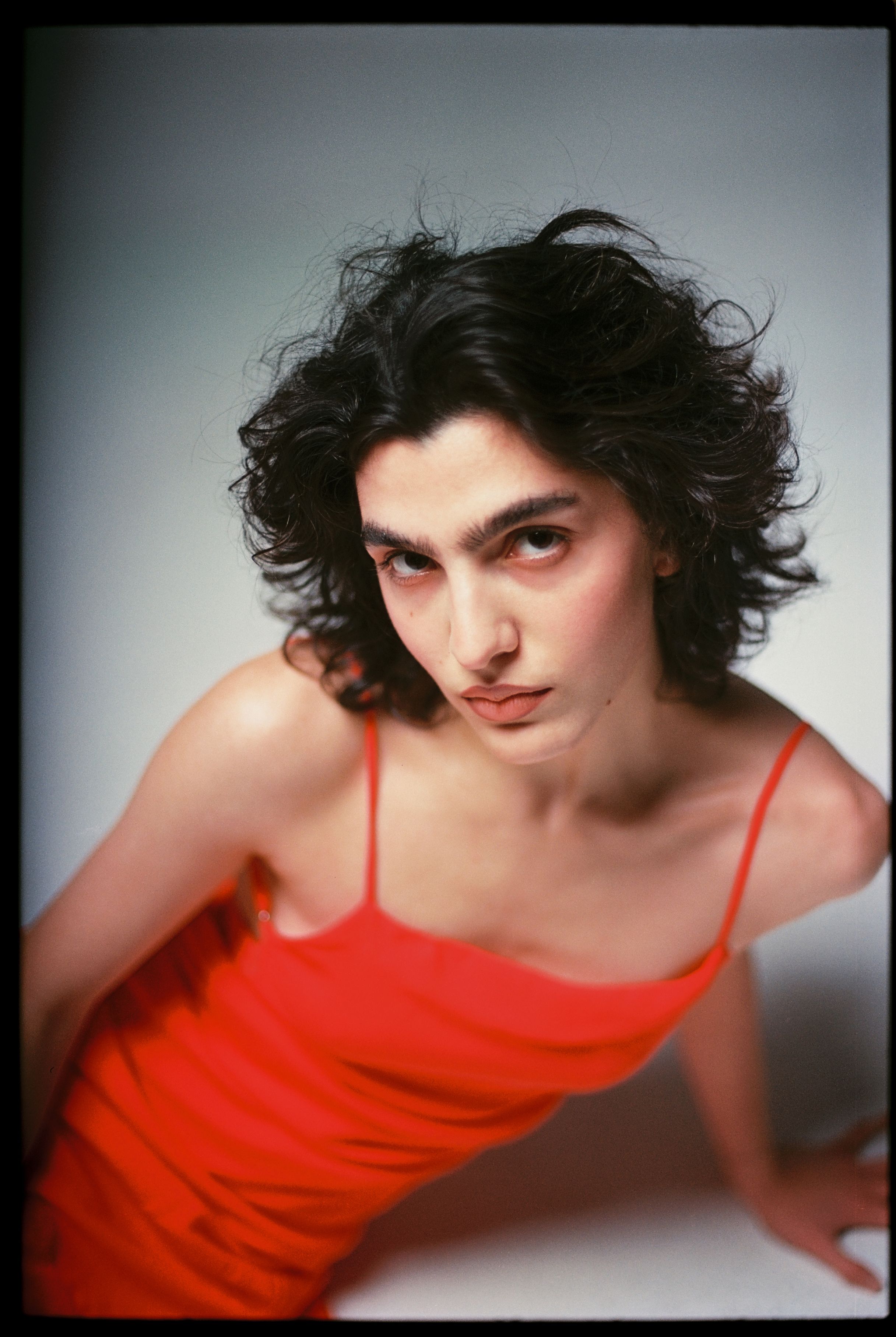 Elegant studio portrait of a woman in a striking red dress with film grain effect.