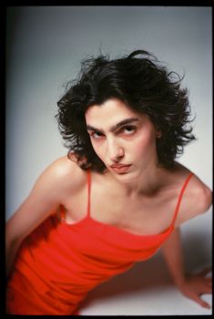 Elegant studio portrait of a woman in a striking red dress with film grain effect.
