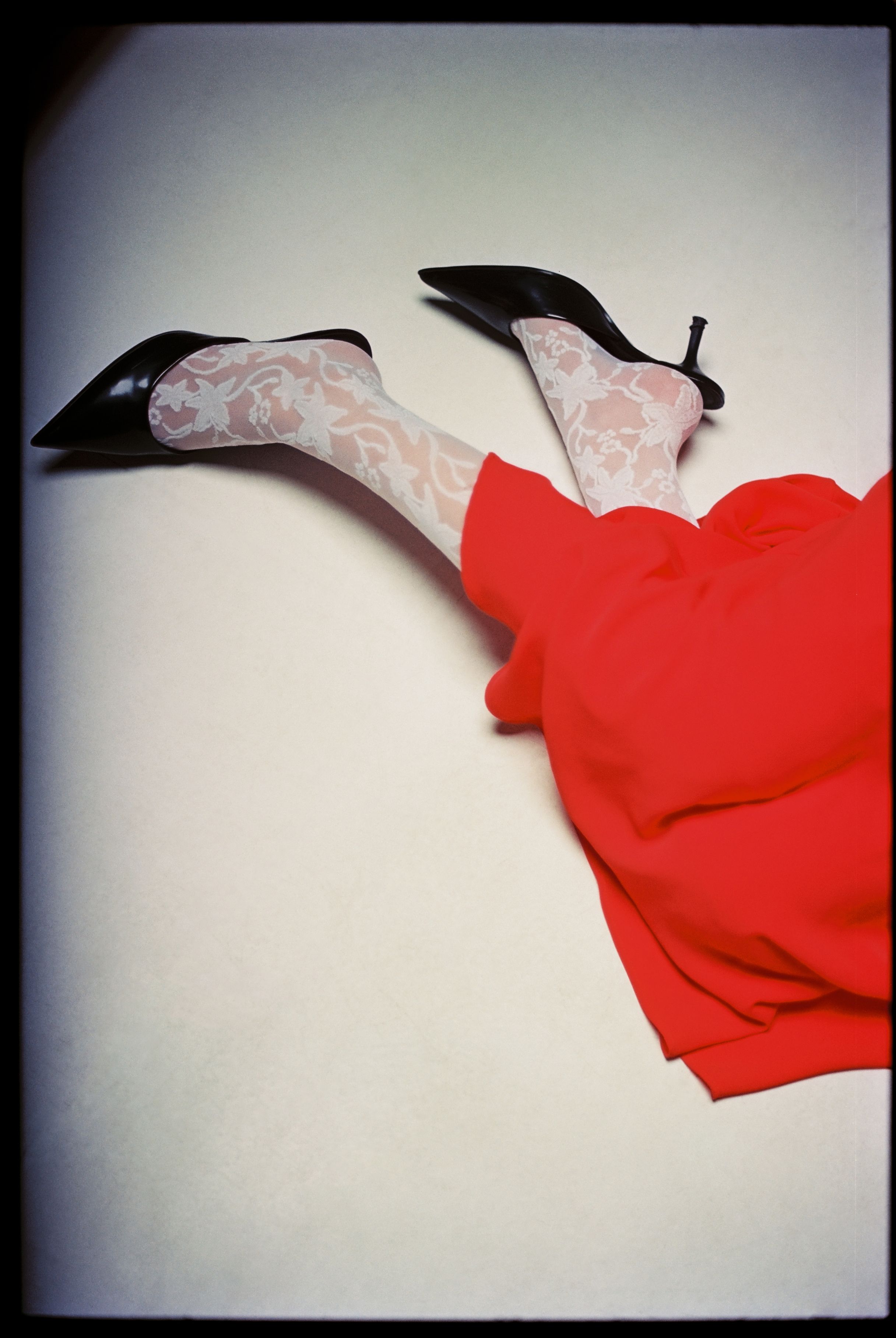 A stylish fashion ensemble featuring a red dress with lace stockings and black heels.