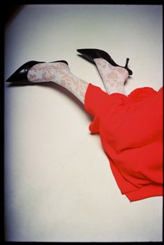 A stylish fashion ensemble featuring a red dress with lace stockings and black heels.