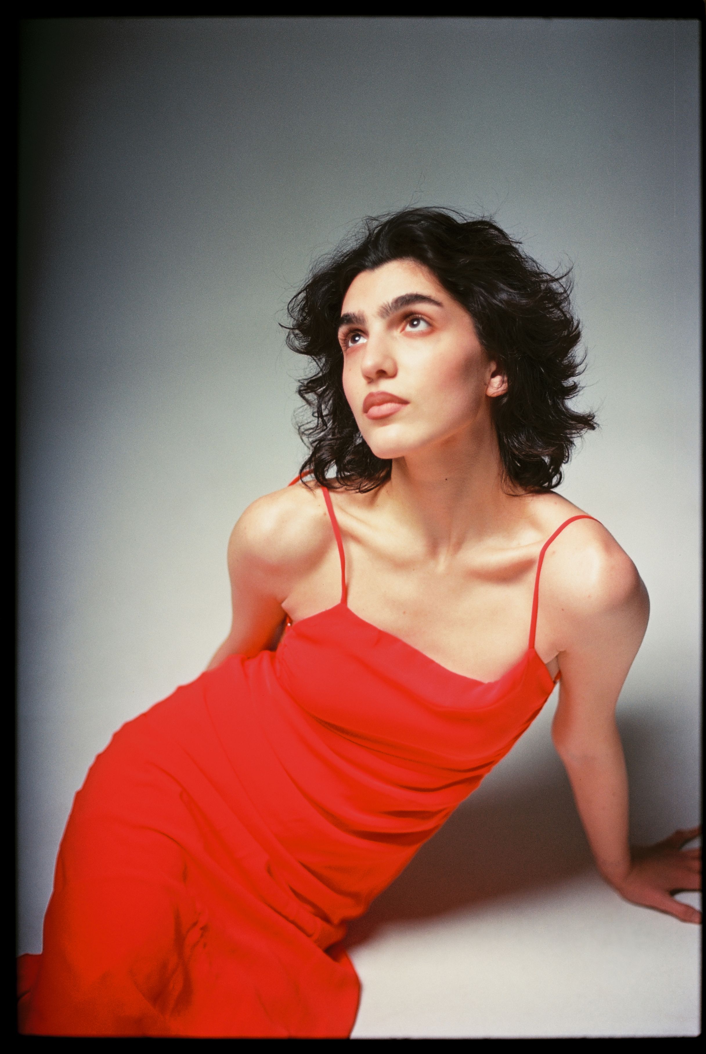 Striking studio portrait of a woman in a red dress with classic beauty and film-like quality.