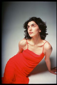 Striking studio portrait of a woman in a red dress with classic beauty and film-like quality.