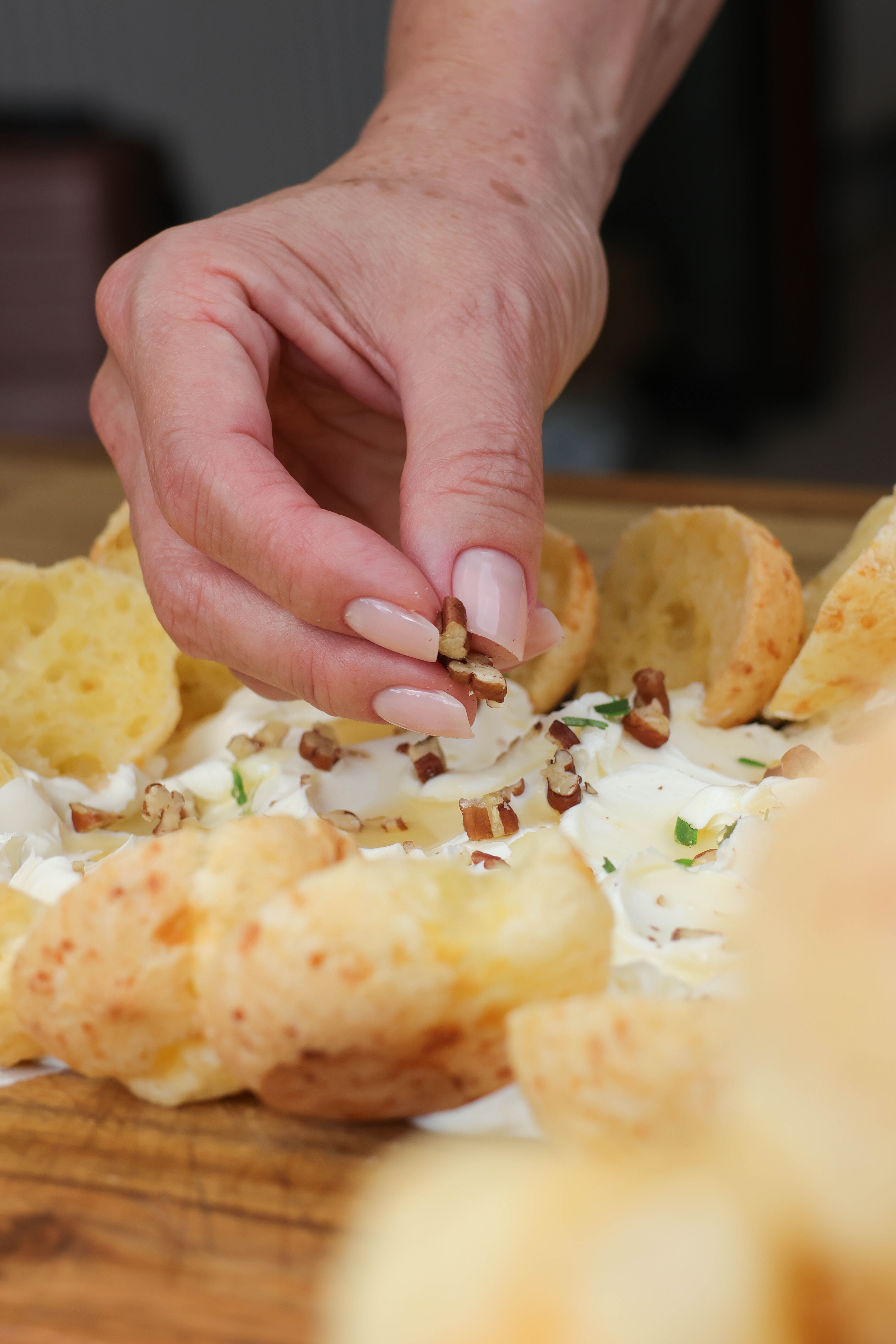 Hand Garnishing Cheese Loaf with Pecans · Free Stock Photo