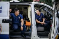 两名穿着制服的护理人员坐在救护车上，微笑着休息片刻