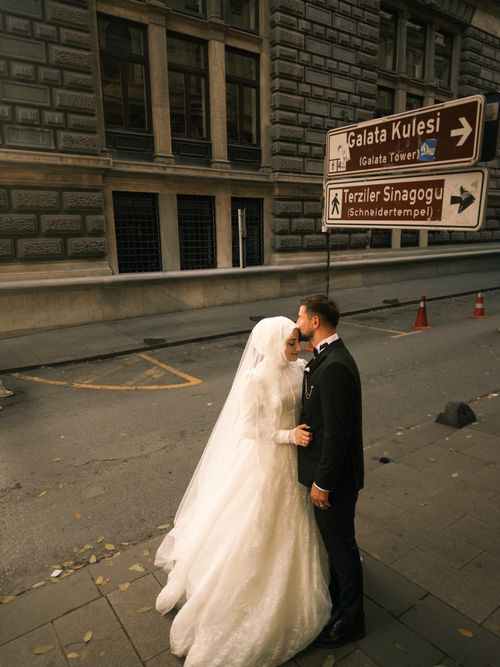 Free A bride and groom sharing a romantic moment near Galata Tower signage in Istanbul. Stock Photo