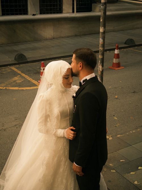 Free Bride and groom in wedding attire share an intimate moment on urban street during day. Stock Photo