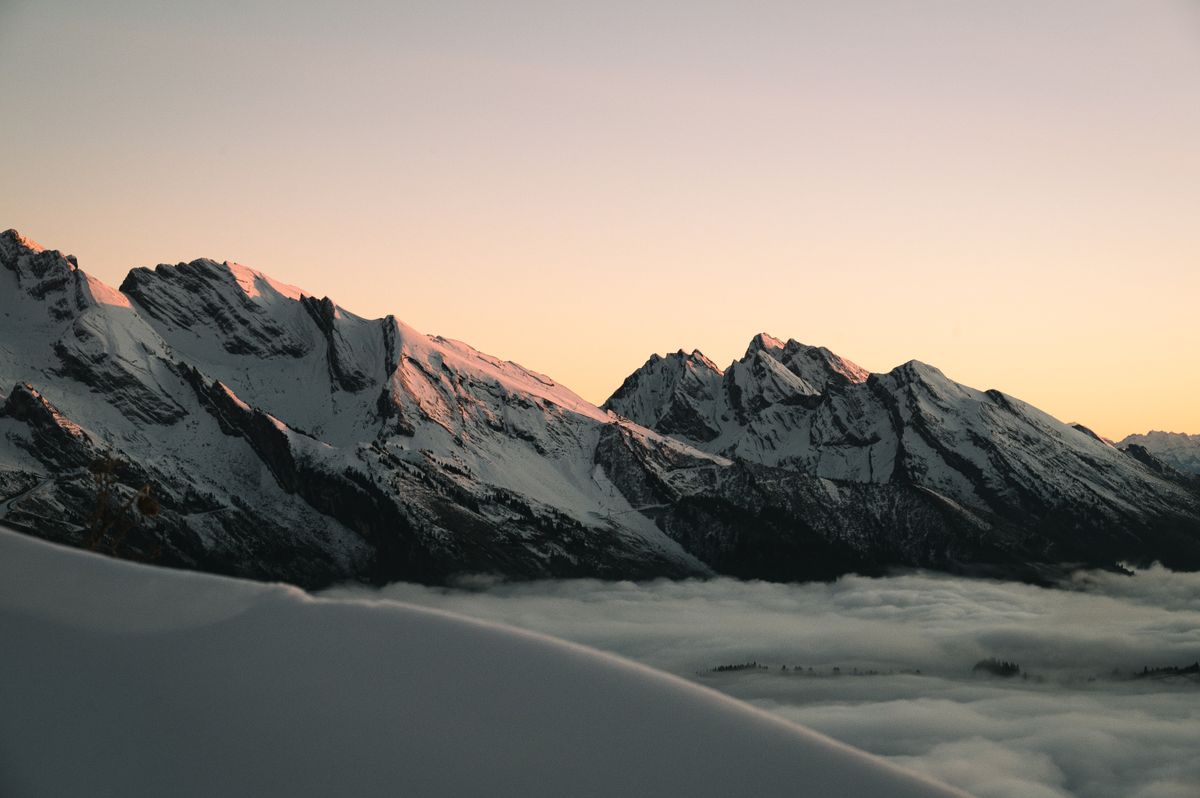 Alpenglow on snowbound peaks above a sea of clouds
