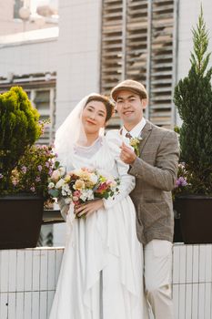 Elegant couple posing in vintage-themed wedding attire in an outdoor garden setting.