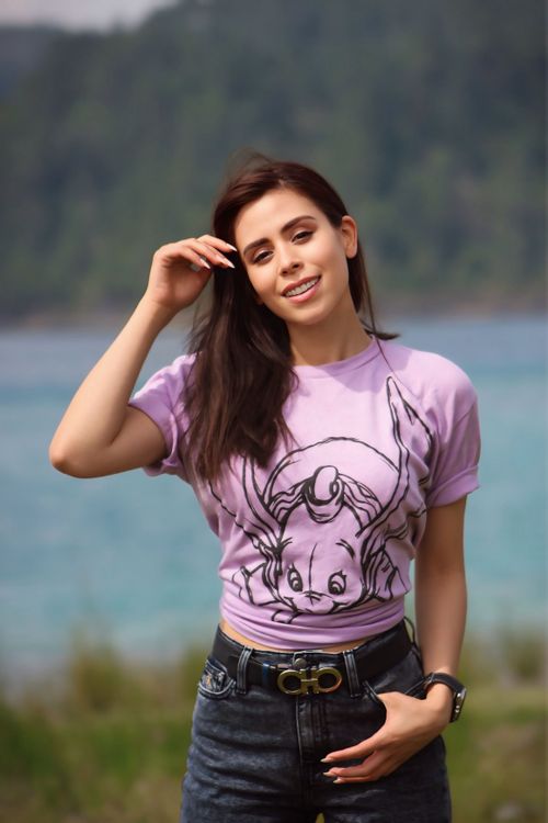 Free A woman in a purple shirt smiles warmly by a tranquil lakeside, exuding a vibe of relaxation and joy. Stock Photo
