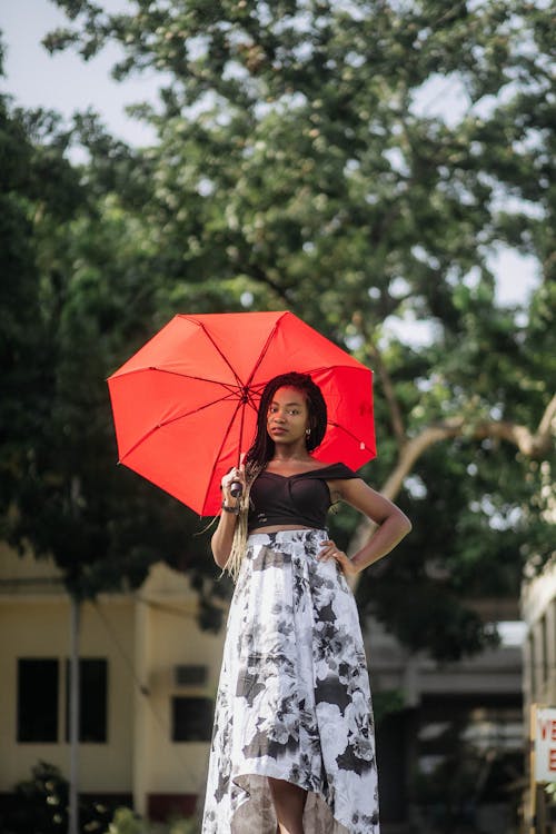 Woman Holding Red Umbrella While Wearing Black Crop Top and White and Black Floral Dress