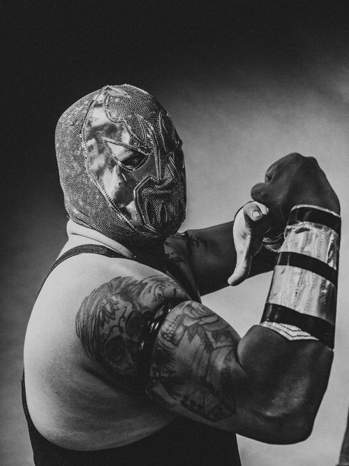 Free Wrestler in a detailed mask striking a strong pose, showcasing tattoos and wrestling attire. Stock Photo