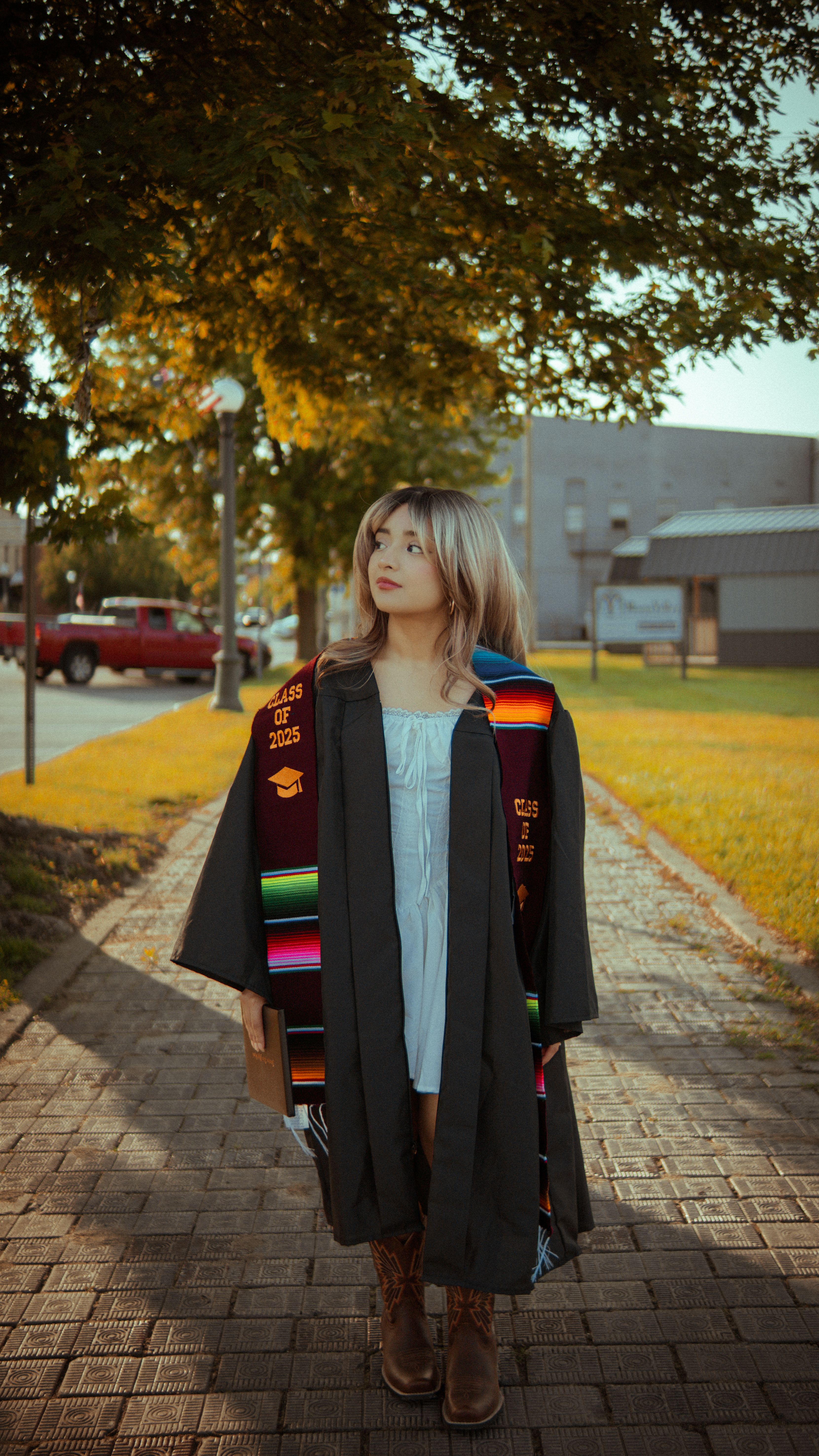 Young Graduate Walking Outdoors in Cap and Gown · Free Stock Photo