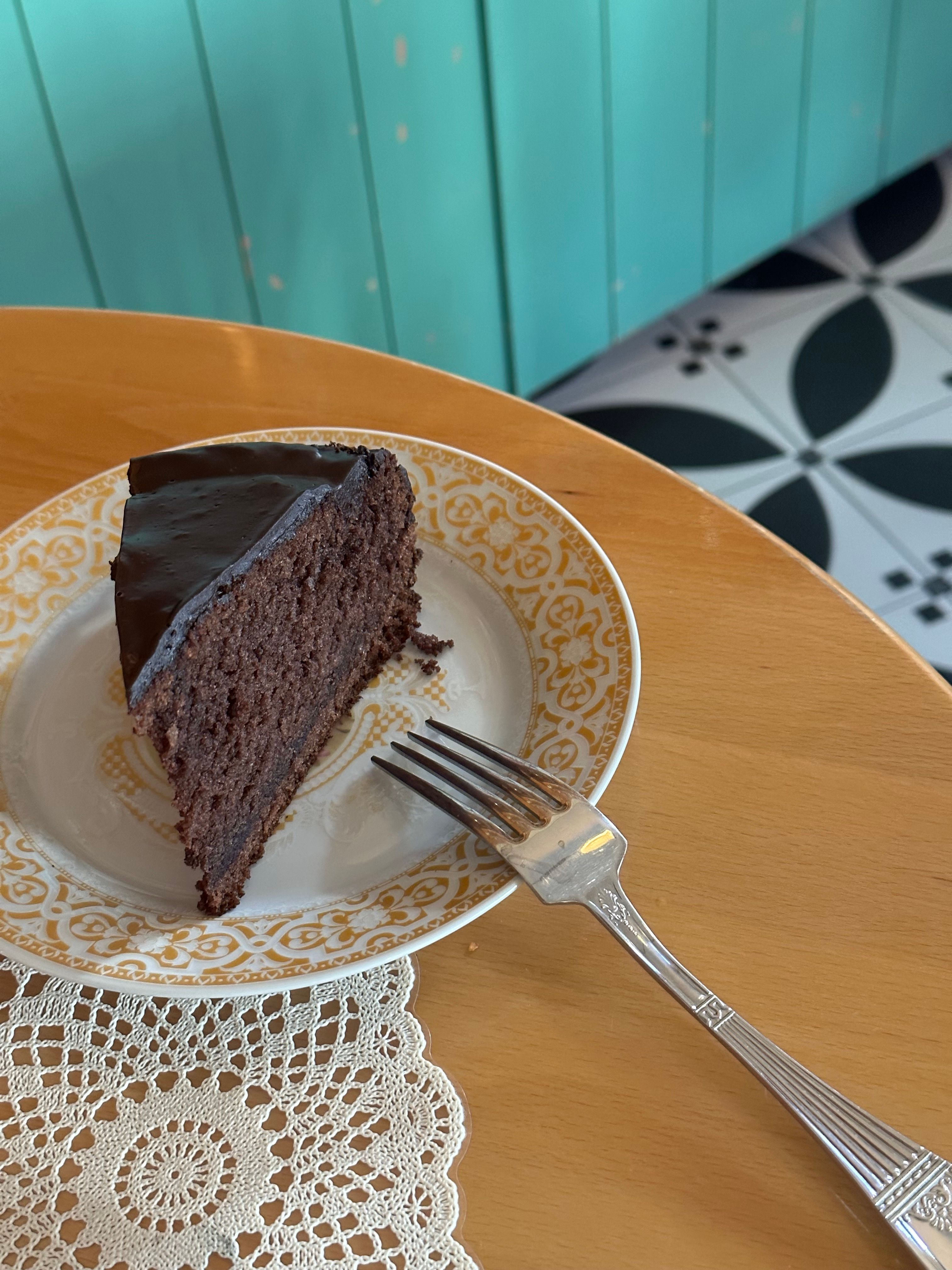 Enjoy a rich chocolate cake slice beautifully presented on a vintage plate, perfect for dessert lovers.