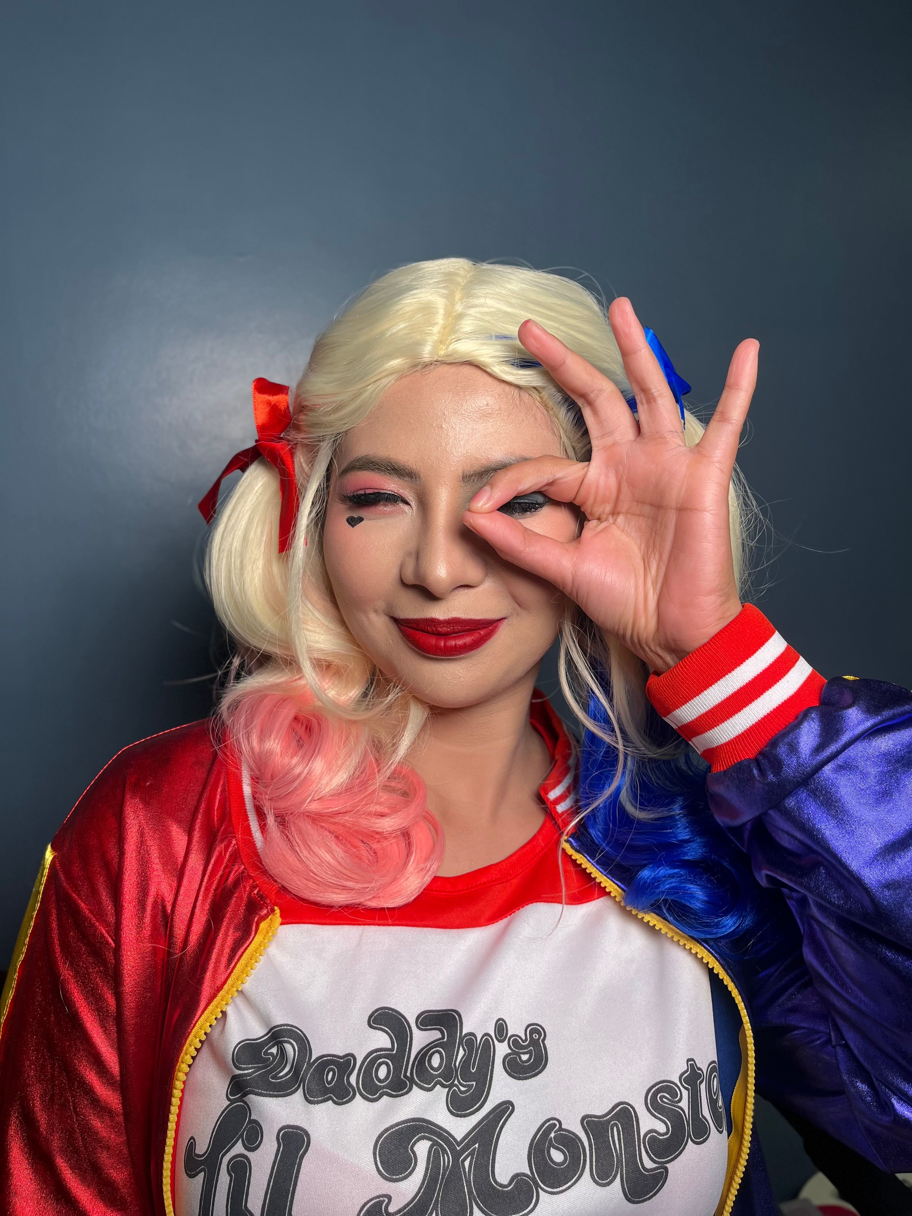 Woman in vibrant cosplay costume making playful sign with her hand.