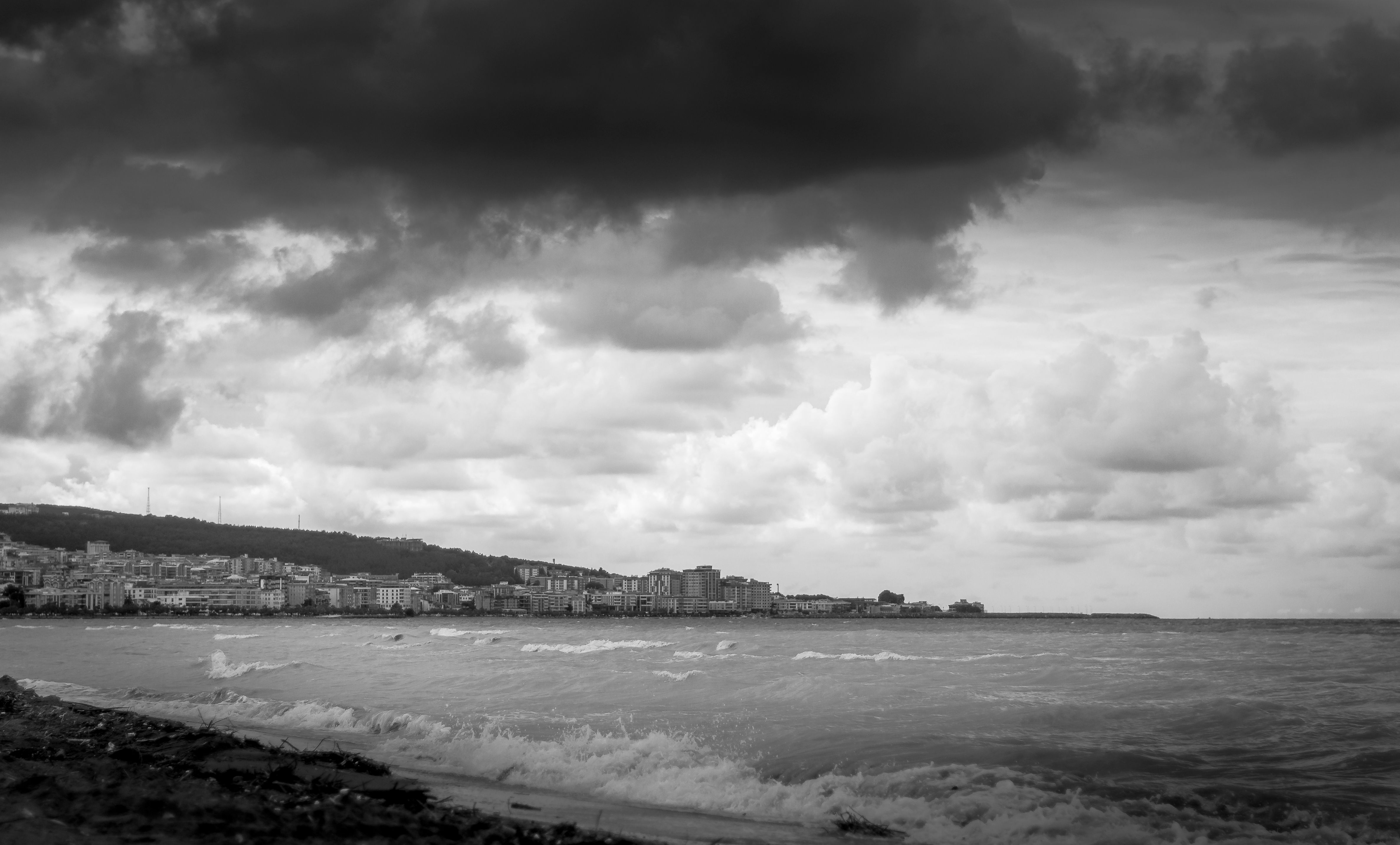 Dark storm clouds over a coastal city skyline