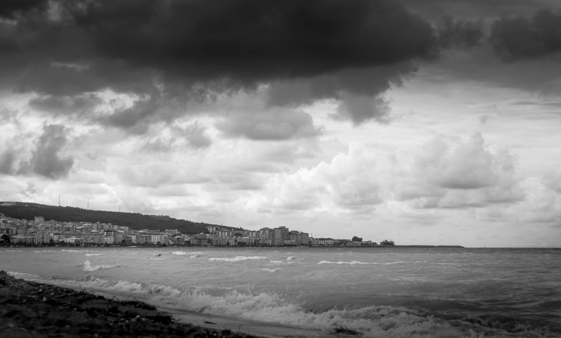 Dark storm clouds over a coastal city skyline