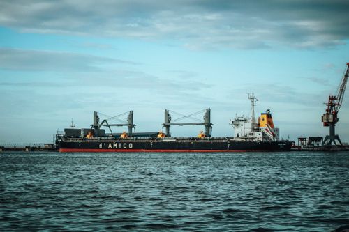 Free A large cargo ship docked at an industrial port under a clear sky, highlighting maritime transport. Stock Photo