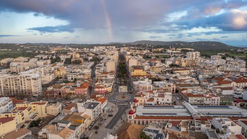 Free Discover Loulé, Portugal from above with a stunning aerial view featuring a beautiful rainbow over the city's skyline. Stock Photo