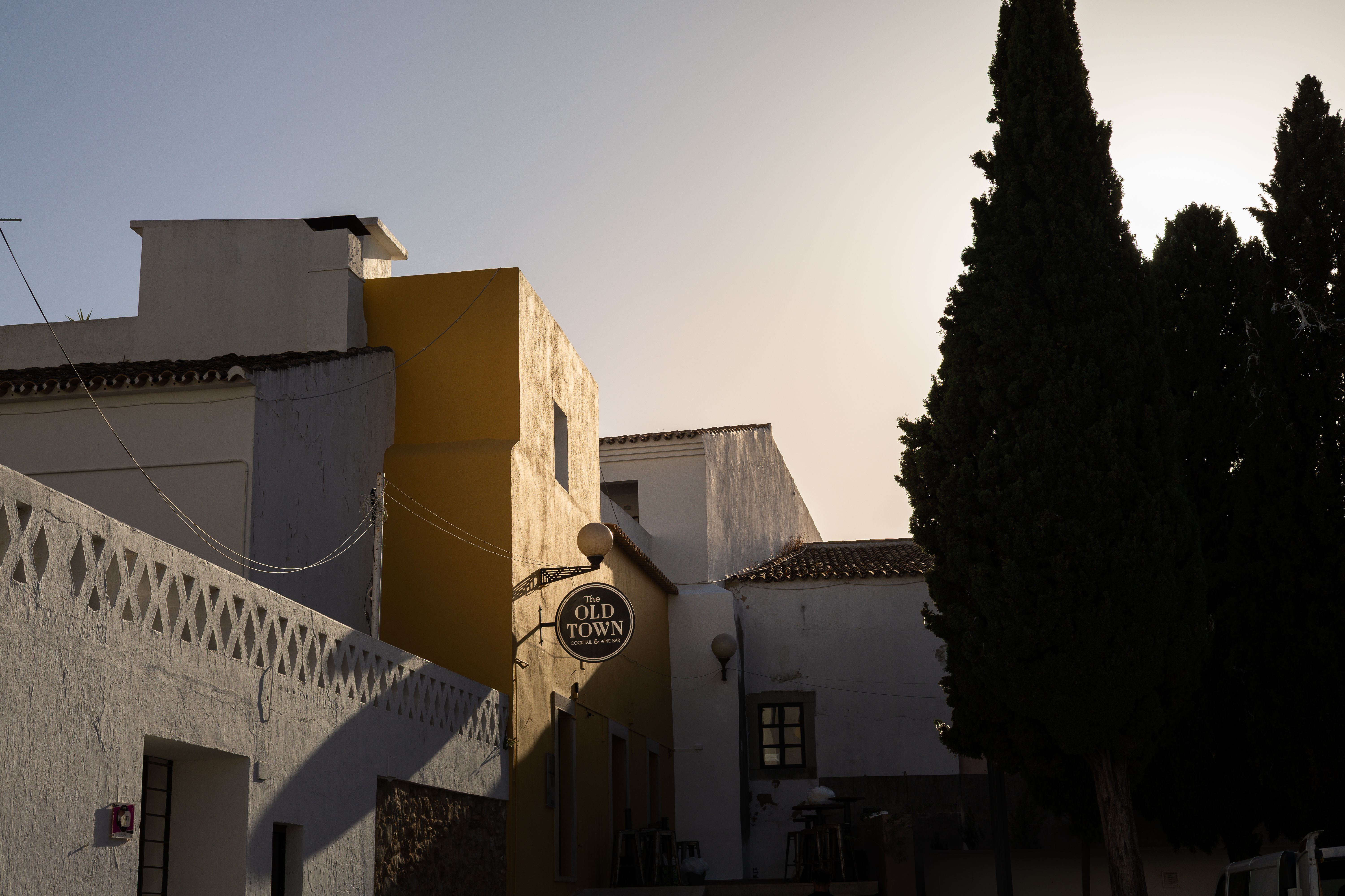 Historic buildings in Loulé's old town at sunset, featuring rustic architecture and tree silhouettes.
