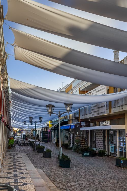 Free Charming street in Loulé, Portugal with decorative canopies and shops under a blue sky. Stock Photo