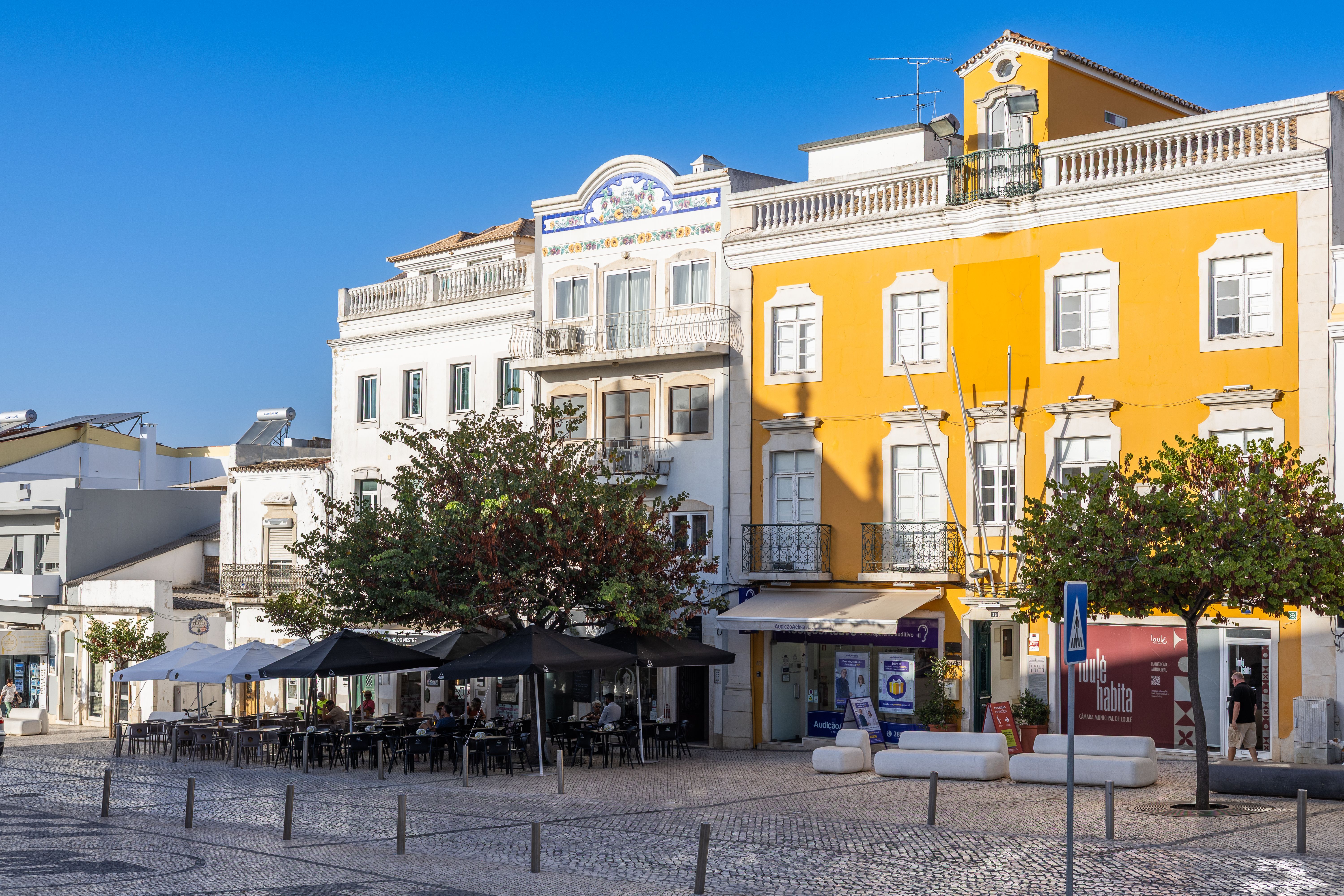 People enjoying a coffee at an outdoor cafe in Portugal, some using mobile phones
