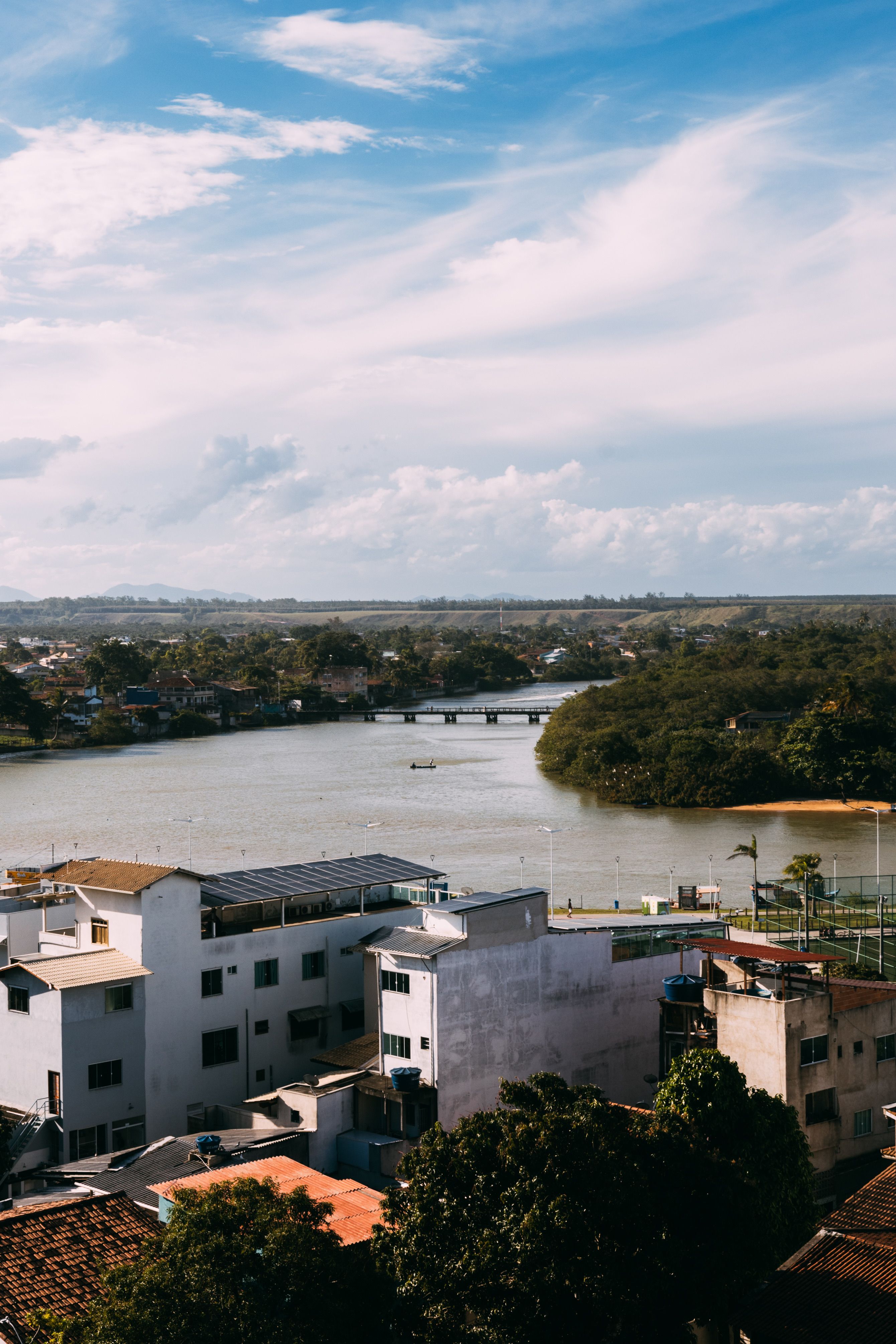 Scenic Urban Riverside with Bridge and Blue Sky · Free Stock Photo