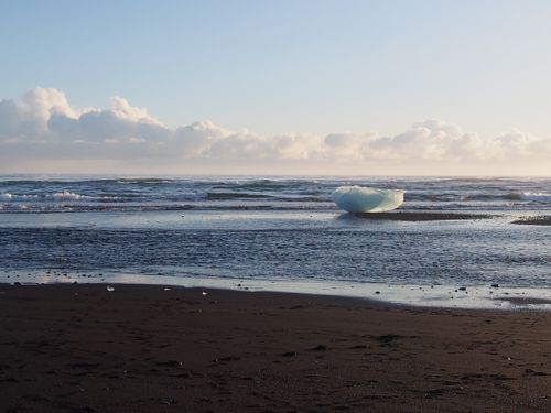 Free A stunning iceberg rests on Iceland's black sand beach under a bright sky. Stock Photo