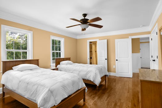 Spacious twin bedroom with natural light and wooden furnishings.
