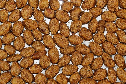 A detailed view of crunchy glazed caramelized nuts spread on a baking sheet, perfect for snacks.