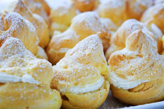Close-up of tempting cream puffs dusted with powdered sugar, perfect for desserts.