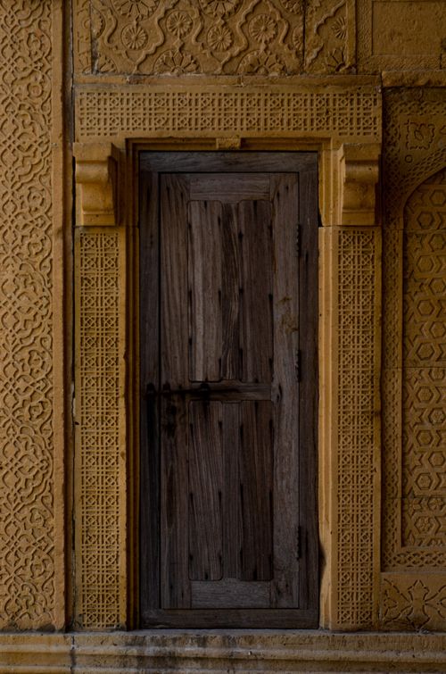 Free Ornate stone wall with a rustic wooden door in intricate design. Stock Photo