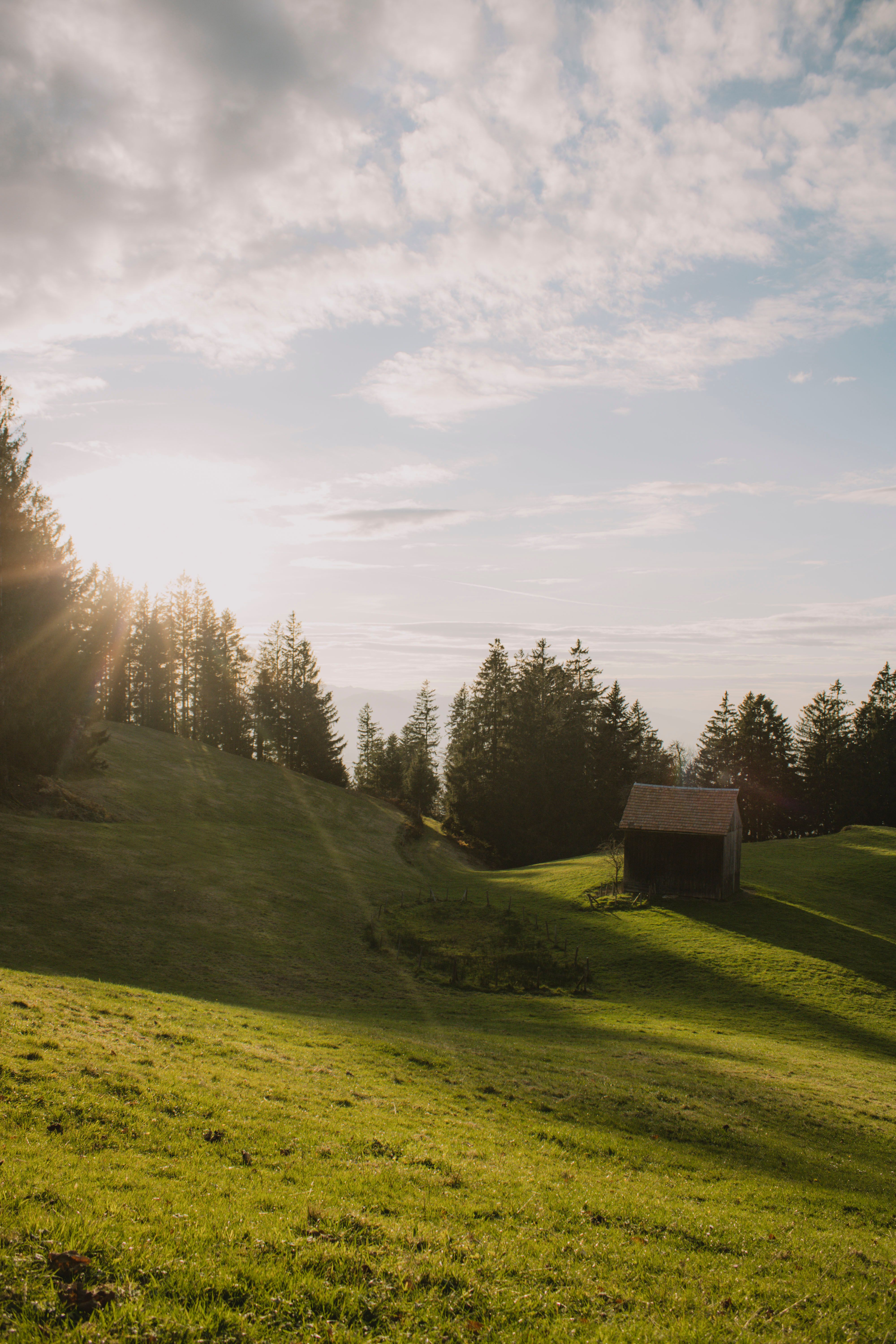 Serene Sunrise Over Lush Green Hills and Rustic Barn · Free Stock Photo