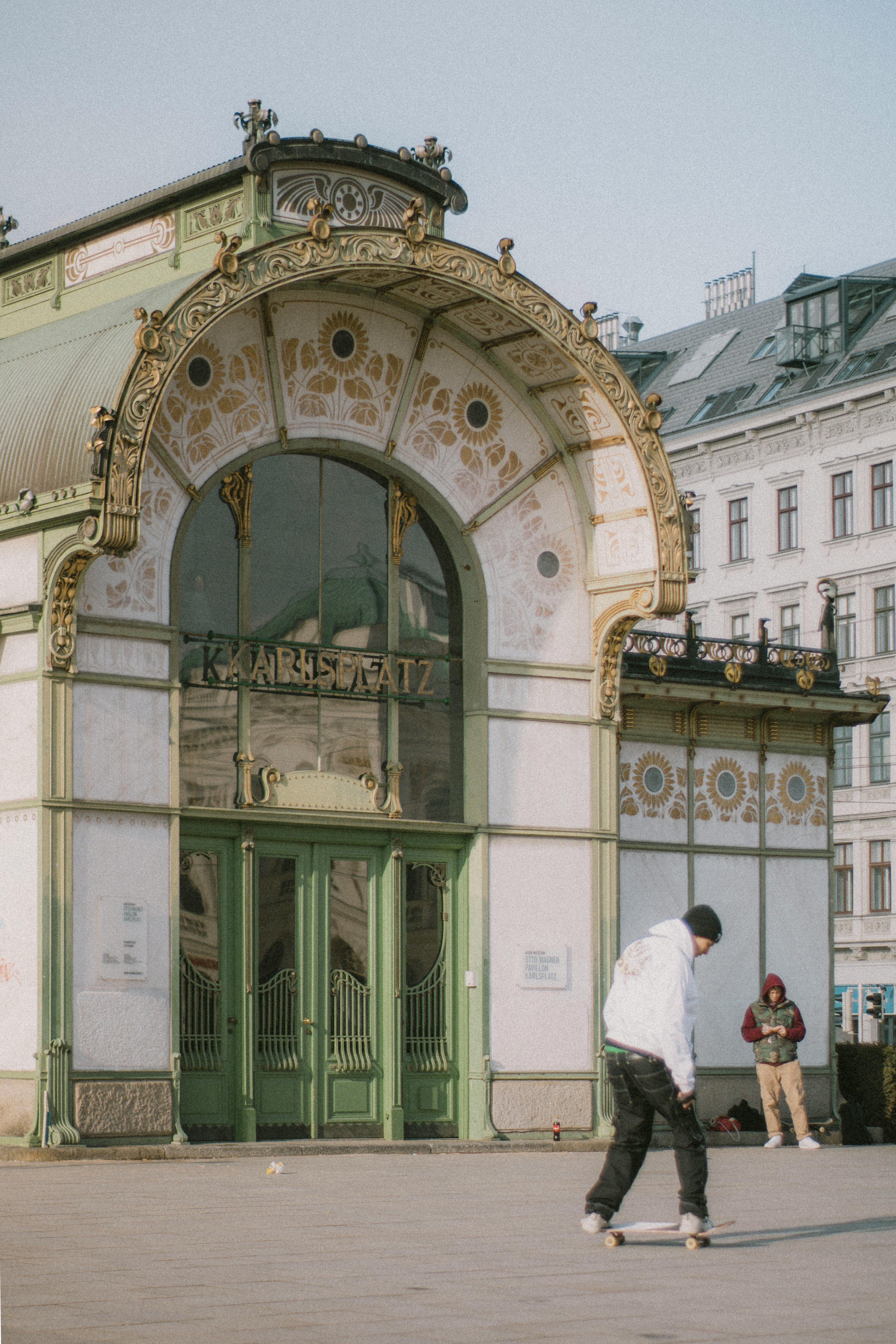 A skateboarder performs a trick outside the historic Karlsplatz Pavilion in Vienna, Austria.