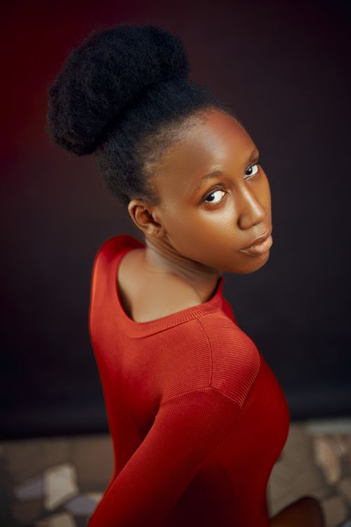 Free Striking portrait of a woman in a bold red dress against a dark background. Stock Photo