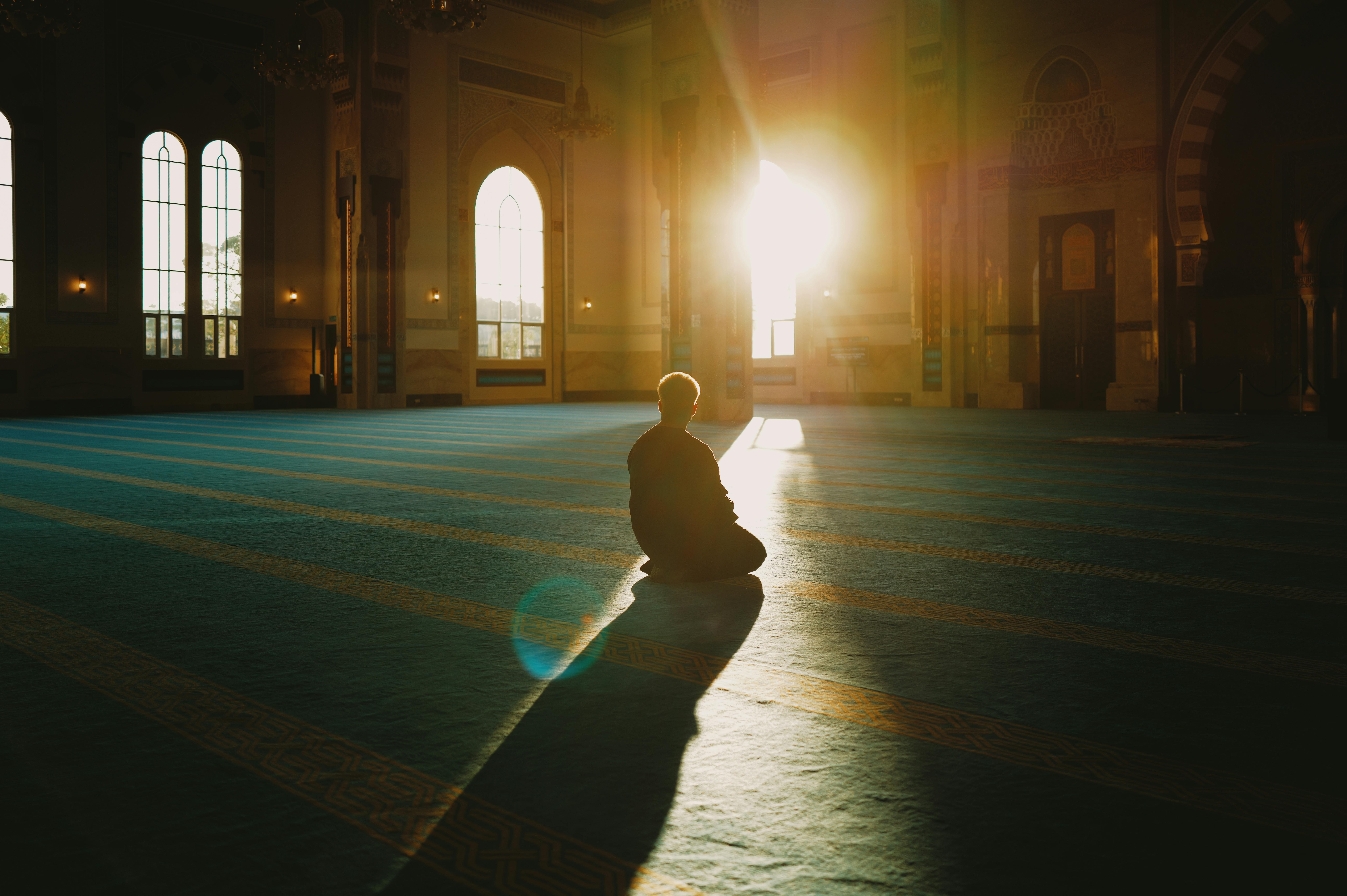 A person praying in a sunlit mosque in Malaysia, capturing tranquility and spirituality.