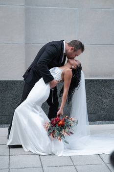 Bride and groom share a romantic kiss, captured elegantly with a floral bouquet.