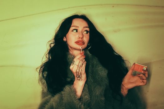 Artistic moody portrait of a woman holding a matchbox indoors.
