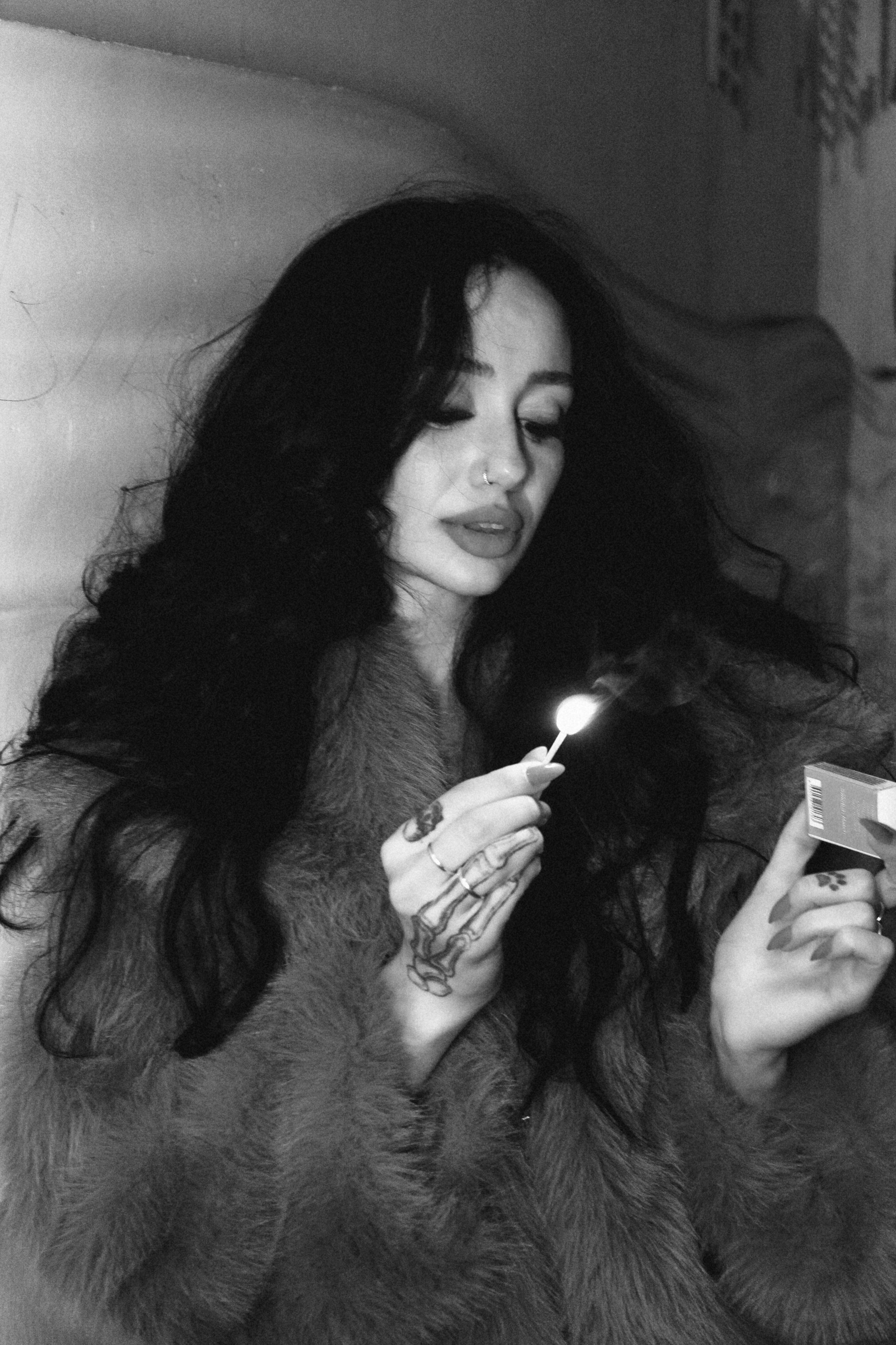 Black and white portrait depicting a woman lighting a match in a contemplative mood.