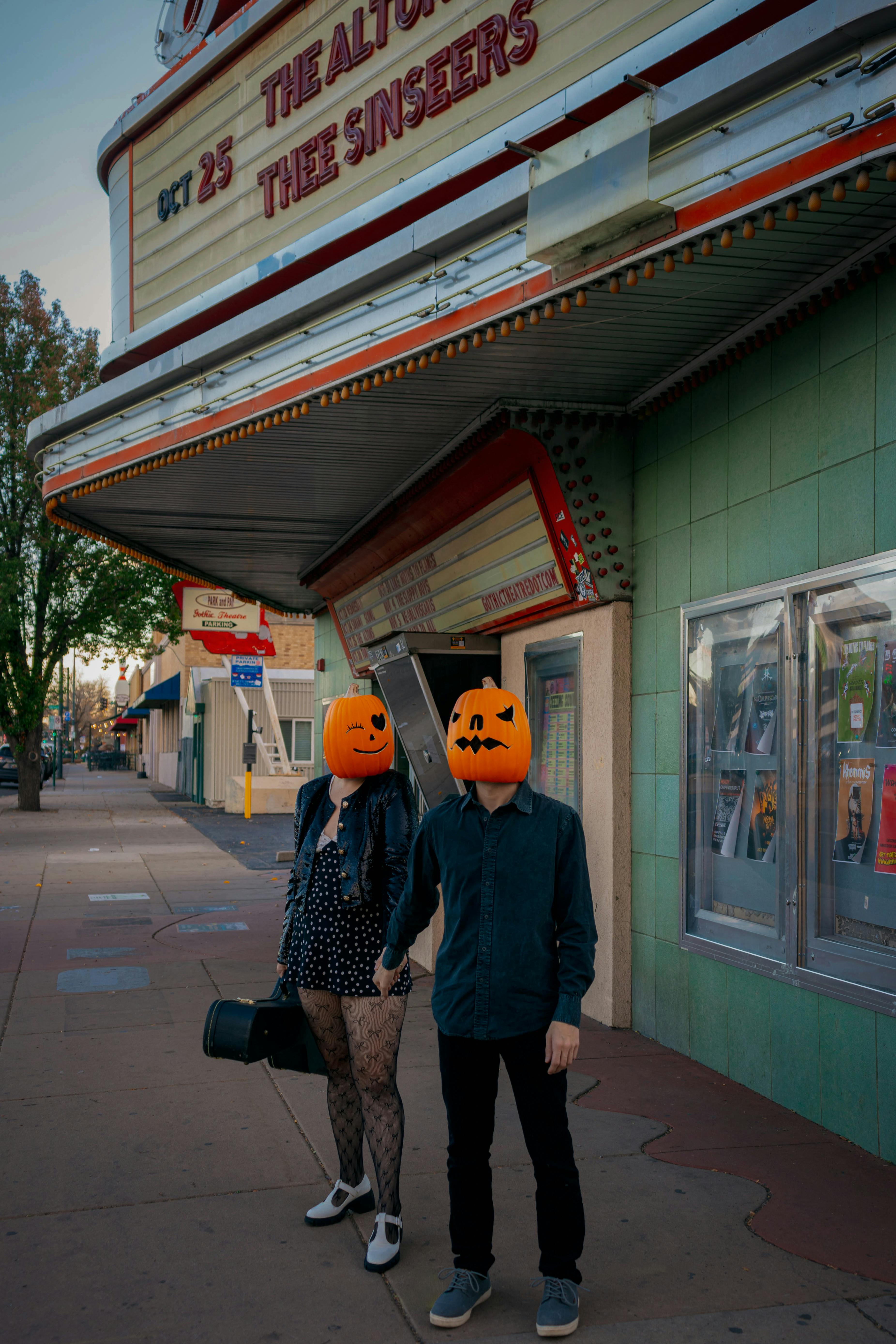 Free Creative couple in Halloween pumpkin masks outside a vintage theater in Englewood, Colorado. Stock Photo