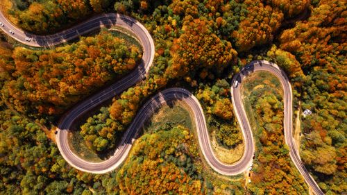 Free Aerial photograph of a serpentine road winding through colorful autumn foliage in a forest. Stock Photo