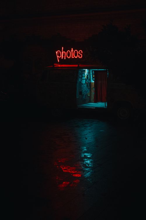 Free Dark photo booth with neon sign at night creating a moody atmosphere. Stock Photo