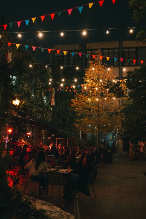 Free Cozy outdoor evening gathering with string lights and festive bunting. Stock Photo