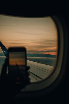 Capturing a scenic airplane wing view through a window during a stunning sunset.