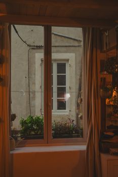 A cozy indoor view of a rustic window in Nîmes, France, reflecting autumn atmosphere.