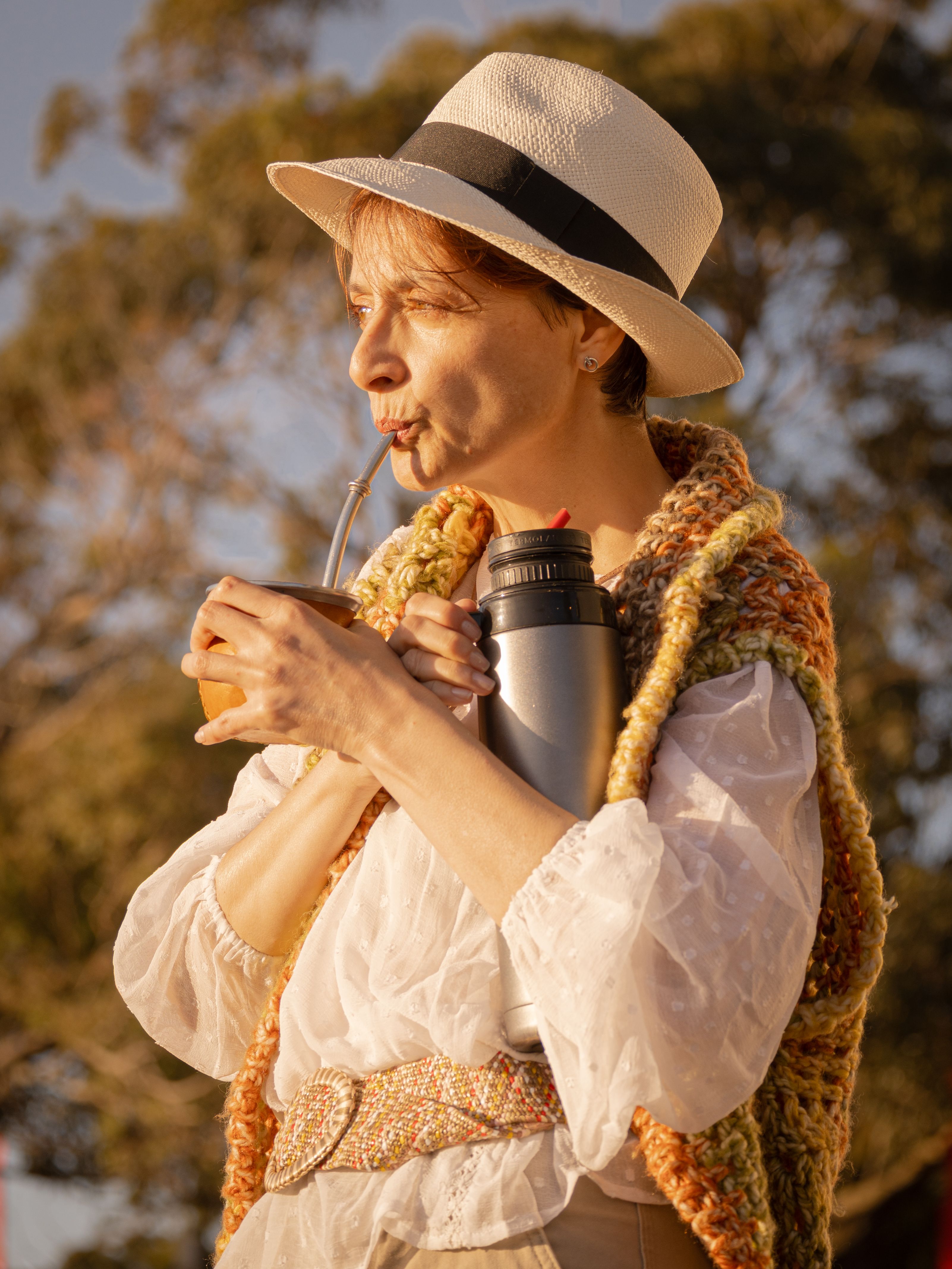 A woman enjoys traditional mate tea outdoors on a sunny day in Montevideo.